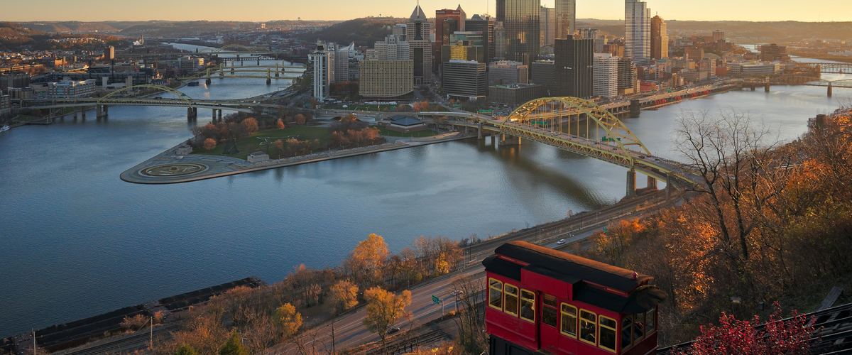 Autumn morning view from the Duquesne Incline: a red incline car, the Point where the three rivers meet, the yellow Fort Pitt Bridge and the downtown skyline