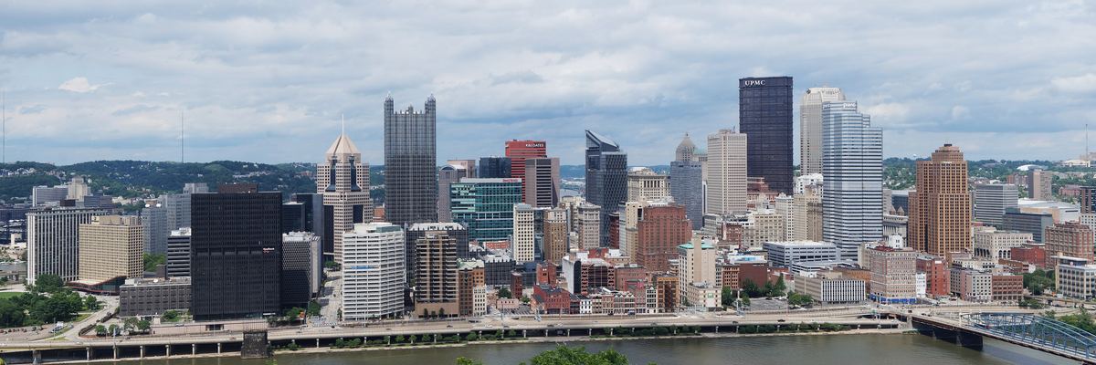 Wide view of the downtown Pittsburgh skyline across the Monongahela River on a cloudy day