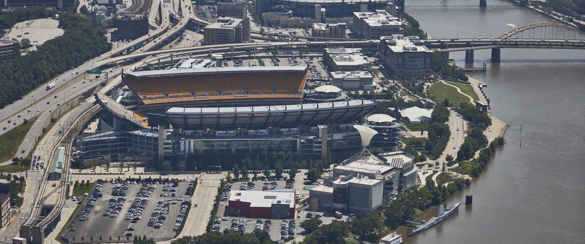 Aerial view of the North Shore football stadium, its parking lots and the Allegheny River with bridges in the distance